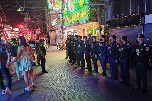 Turistpolitiet på oppstilling før en inspeksjon i Walking Street i Pattaya. Med en cannabis-forretning som annonserer sine varer høylytt i bakgrunnen.